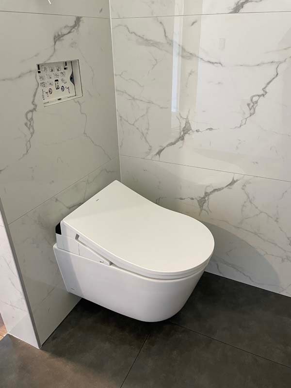 Modern wall-mounted toilet in a marble tiled bathroom