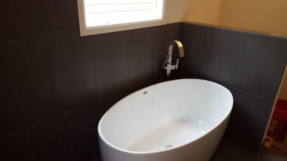 Modern oval bathtub in a dark-tiled bathroom