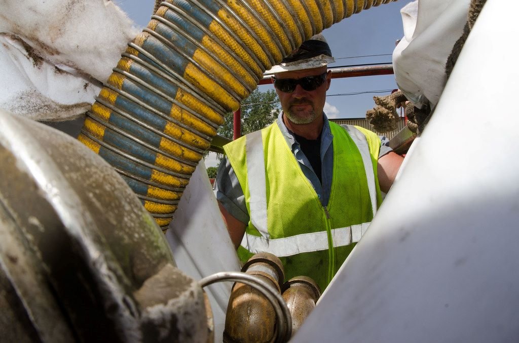 Worker with suction hose at industrial site