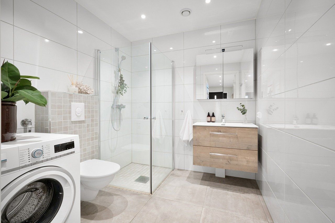 Modern bathroom with white tiles and wooden vanity.