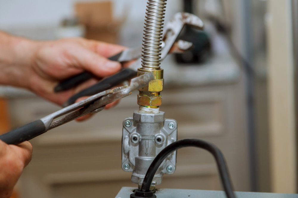 Technician adjusting gas valve with pliers indoors