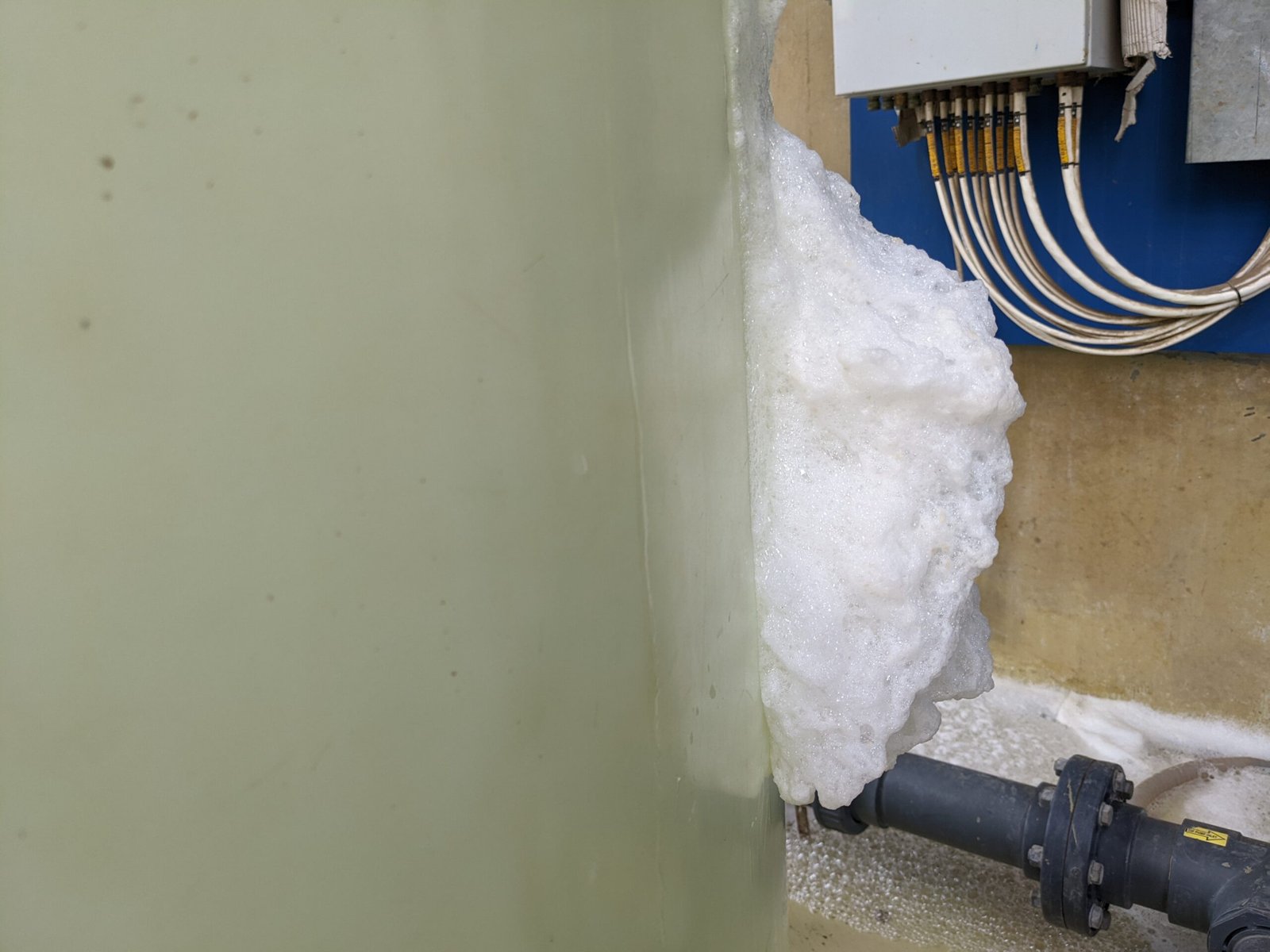 Foam overflowing near industrial pipe and electrical box