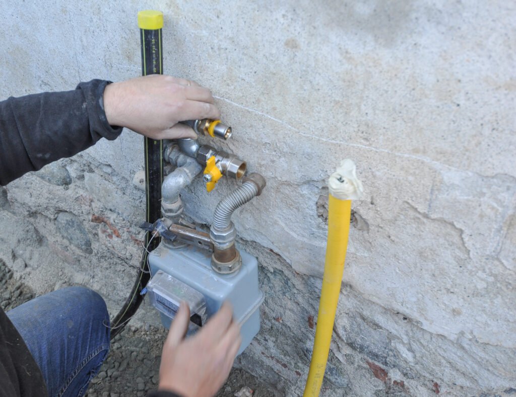 Technician adjusting gas meter installation on wall