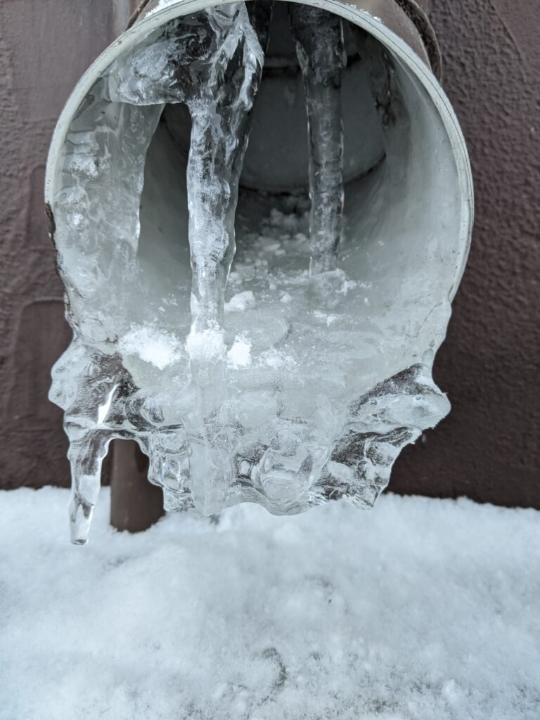 Frozen pipe covered in ice and snow